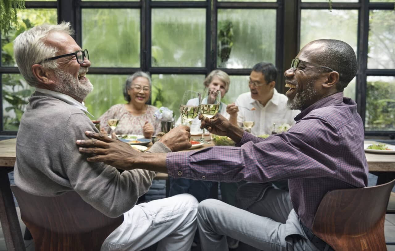 Group of older friends laughing at a dinner party.
