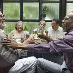 Group of older friends laughing at a dinner party.