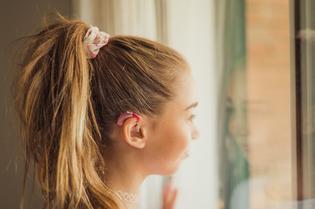 Teen girl wearing hearing aids at home.